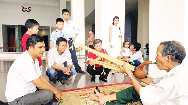 Nghệ nhân Ama Hloan ở buôn Akô Dhông, phường Buôn Ma Thuột, tỉnh Đắk Lắk giới thiệu nhạc cụ Đinh Năm với du khách.