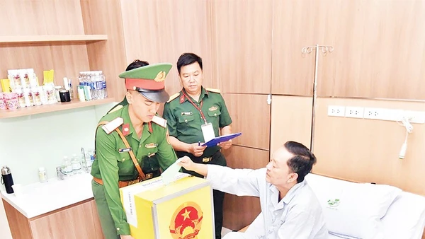 Bệnh nhân Bệnh viện Quân y 175 bỏ phiếu vào thùng phiếu di động. (Ảnh TÙNG LÂM)
