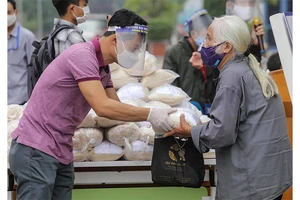Tình nguyện viên phát gạo cho người nghèo bị ảnh hưởng do dịch Covid-19 tại quận Hai Bà Trưng (Hà Nội). Ảnh: CTV