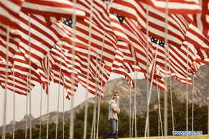 Một người phụ nữ đi dưới những lá cờ tại Trường đại học Pepperdine, thành phố Malibu, bang California, Mỹ, ngày 11-9-2020. (Ảnh: Xinhua)