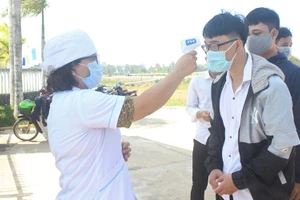 Thí sinh Trường THPT Hùng Vương (huyện Thăng Bình) được kiểm tra nhiệt độ khi đến làm thủ tục dự thi.
