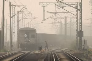 Một người phụ nữ băng qua đường ray khi tàu chở hàng chạy qua, vào một ngày sương mù ở New Delhi, Ấn Độ. Ảnh chụp ngày 12/11/2021. Ảnh: Reuters.