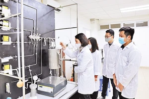 GS,TS Lê Minh Thắng cùng các cộng sự trong phòng thí nghiệm bên sơ đồ công nghệ xử lý khí thải. Ảnh: Ngô Hà