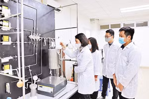 GS,TS Lê Minh Thắng cùng các cộng sự trong phòng thí nghiệm bên sơ đồ công nghệ xử lý khí thải. Ảnh: Ngô Hà