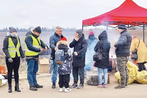 Một em bé sơ tán lạc mẹ đang được các tình nguyện viên Nga giúp.