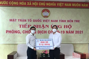Quyền Chủ tịch Ủy ban Mặt trận Tổ quốc Việt Nam tỉnh Bến Tre Nguyễn Phúc Linh (phải) nhận bảng tượng trưng số tiền 3 tỷ đồng hỗ trợ tỉnh Bến Tre.