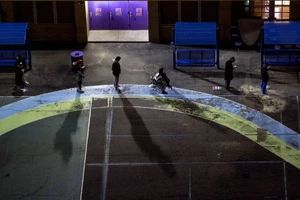 Cử tri xếp hàng tại sân chơi của một trường tiểu học tại bang New York từ sáng sớm để chờ điểm bỏ phiếu mở cửa. (Ảnh: AP)