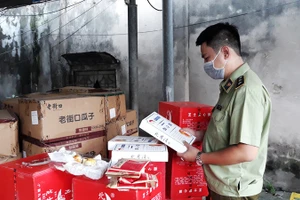 Cán bộ quản lý thị trường kiểm tra chất lượng sản phẩm bánh, kẹo nhập khẩu. (Ảnh: NGUYÊN TRANG)