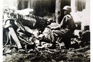 Chiến sĩ Trần Thành, đoàn viên Thanh niên cứu quốc Hoàng Diệu, ôm bom ba càng, sẵn sàng tiêu diệt xe tăng địch trên đường phố Thủ đô Hà Nội ngày 23-12-1946 - những ngày đầu Toàn quốc kháng chiến, với ý chí "Quyết tử cho Tổ quốc quyết sinh". Ảnh: Nguyễn Bá Khoản (TTXVN)