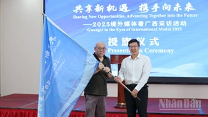 Ông Lê Phan, Chủ nhiệm Văn phòng Báo chí Chính quyền nhân dân khu tự trị dân tộc Choang Quảng Tây trao cờ cho đại diện truyền thông nước ngoài tham dự chương trình.