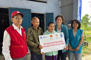 Đại diện Chương trình Phát triển Liên hợp quốc (UNDP) trao tiền hỗ trợ cho gia đình bị ảnh hưởng bởi bão lũ.