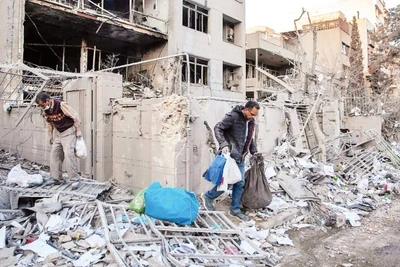 Người dân thu dọn đống đổ nát sau một vụ không kích tại Iran. (Ảnh: THE NEW YORK TIMES)