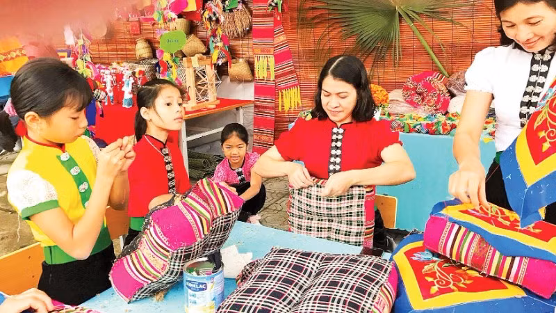 Hướng dẫn trẻ cách hoàn thiện đệm thổ cẩm tại phường Nghĩa Lộ.