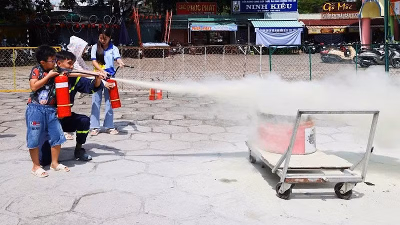 Các em thiếu nhi thực hành dùng bình chữa cháy dập lửa tại buổi tập huấn.