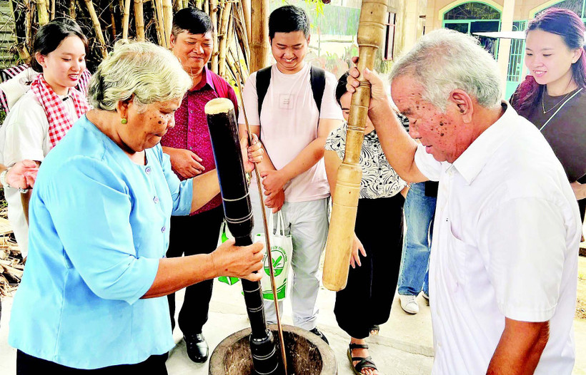 Vợ chồng ông Thạch Sang giã cốm dẹp cho khách du lịch xem.