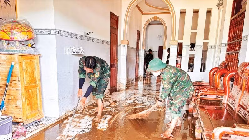 Chiến sĩ Trung đoàn bộ binh 812 giúp đồng bào Chăm ở thôn Lâm Giang (xã Hàm Thuận Bắc) dọn bùn.