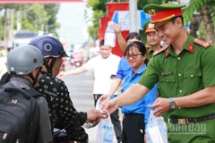 Cán bộ, chiến sĩ công an phát nước suối và khăn lạnh cho người dân về quê nghỉ lễ.