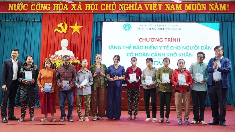 Phó Giám đốc Bảo hiểm xã hội tỉnh Trần Ngọc Tuấn cùng các đại biểu trao tặng thẻ bảo hiểm y tế cho người dân. (Ảnh: BTC)