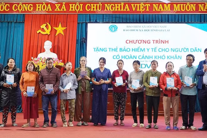 Phó Giám đốc Bảo hiểm xã hội tỉnh Trần Ngọc Tuấn cùng các đại biểu trao tặng thẻ bảo hiểm y tế cho người dân. (Ảnh: BTC)