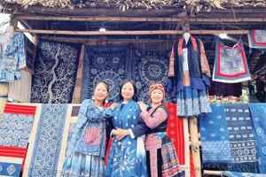 Hàng Y Cô (ngoài cùng bên trái) tại gian hàng thổ cẩm H'Mông của mình.