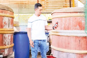 Anh Võ Nguyên Tùng, Trưởng ban làng nghề truyền thống nước mắm Cửa Khe, bên những thùng gỗ ủ mắm của mình.