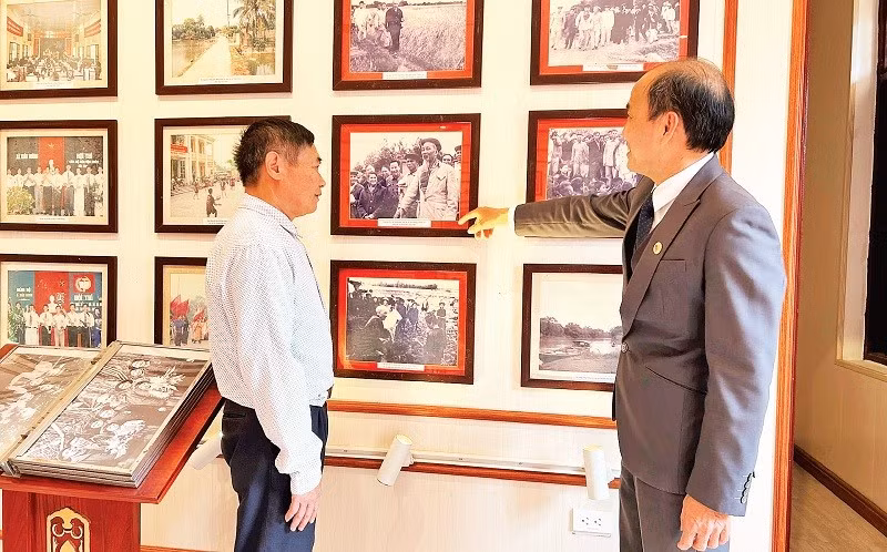 Ông Phùng Văn Tiệp (bên phải), Trưởng phòng Văn hóa-Xã hội xã Dân Hòa giới thiệu cho khách tham quan các hình ảnh về Chủ tịch Hồ Chí Minh tại Nhà lưu niệm Chủ tịch Hồ Chí Minh tại xã Dân Hòa.