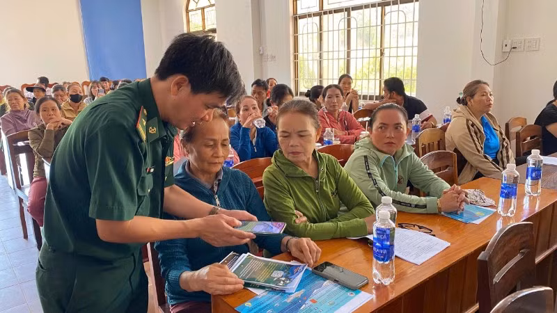 Cán bộ Đồn Biên phòng Tam Quan Nam phát tờ rơi tuyên truyền và hướng dẫn ngư dân quét mã QR.