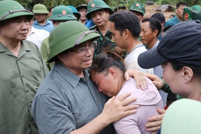Thủ tướng chia sẻ với nỗi đau mất người thân của người dân vùng lũ quét. (Ảnh TTXVN)