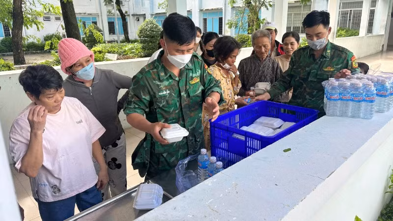 Cán bộ, chiến sĩ Đồn Biên phòng Xuân Đài phát những hộp cơm và chai nước uống 0 đồng cho người dân vùng thiên tai.