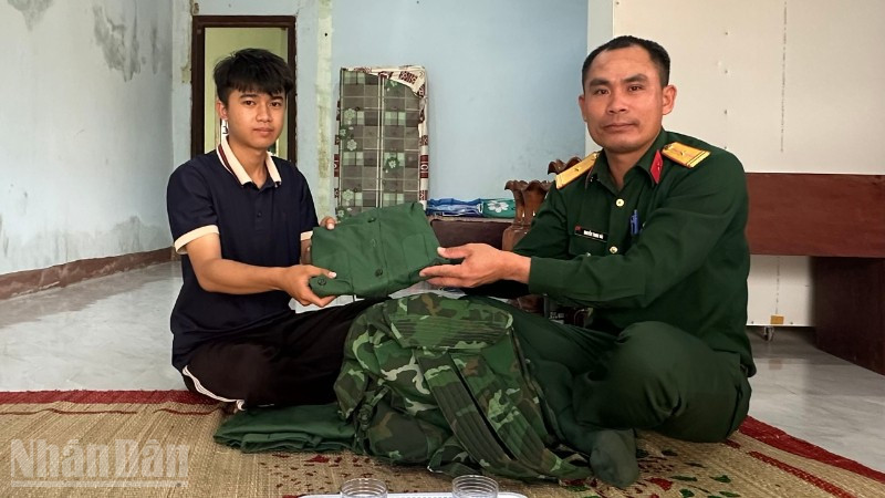 Thanh niên Vi Hồng Minh nhận quân phục mới từ cán bộ Ban chỉ huy Quân sự xã Ia Rvê.