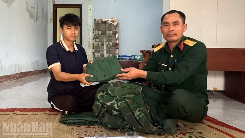 Thanh niên Vi Hồng Minh nhận quân phục mới từ cán bộ Ban chỉ huy Quân sự xã Ia Rvê.