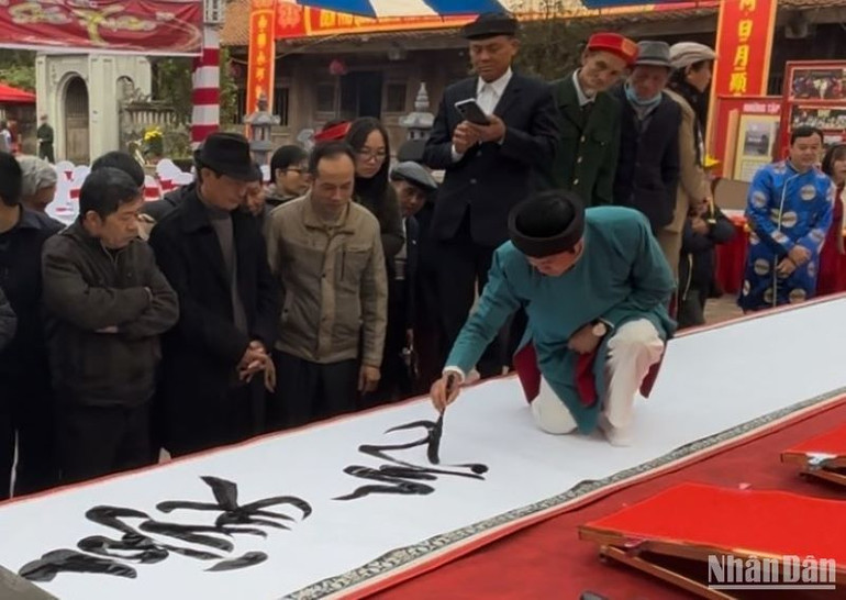 Người dân đang xem hội viên Câu lạc bộ Hán Nôm và thư pháp Bảo tàng tỉnh Thái Bình viết chữ "Hào khí Đông A".