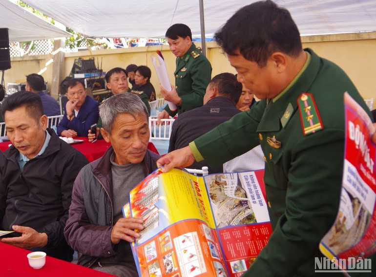 Bộ đội Biên phòng tỉnh Thái Bình phát tờ rơi hướng dẫn phòng chống hỏa hoạn trên tàu cá cho ngư dân.
