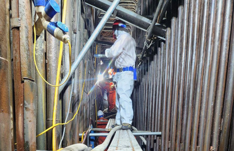 Công nhân sửa chữa lò trong không gian chật hẹp, nhiệt độ cao.