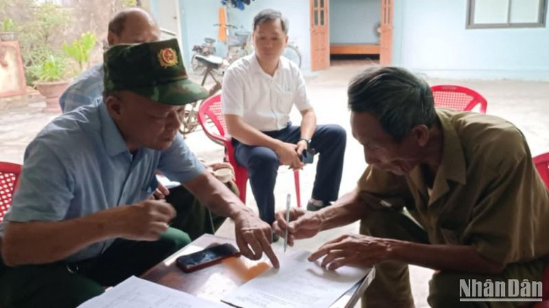 Tổ công tác thôn Trung Lập (xã Vũ Hội, huyện Vũ Thư) hướng dẫn người dân lấy ý kiến sắp xếp bộ máy hành chính cấp tỉnh, cấp xã năm 2025 thông qua mẫu phiếu in sẵn.