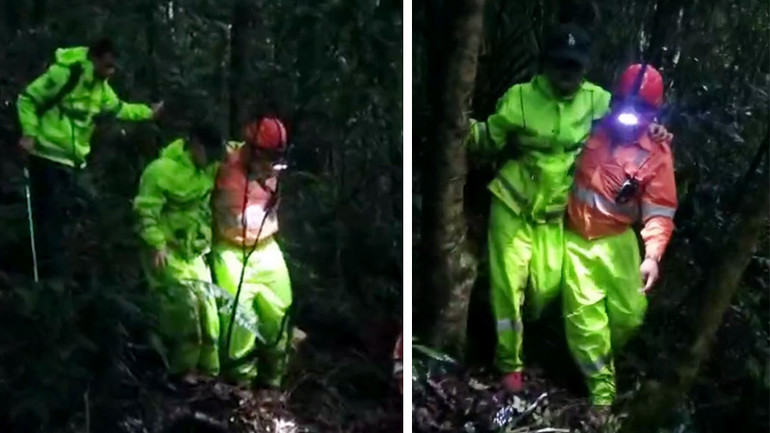 Lực lượng cứu hộ dìu 2 du khách ra khỏi khu rừng trên địa hình phức tạp.