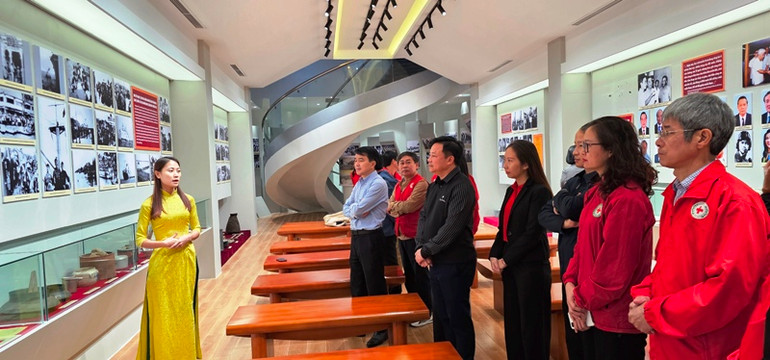 Các đại biểu, du khách nghe giới thiệu về sự kiện tập kết năm 1954 cùng các hiện vật, hình ảnh, tư liệu lịch sử.