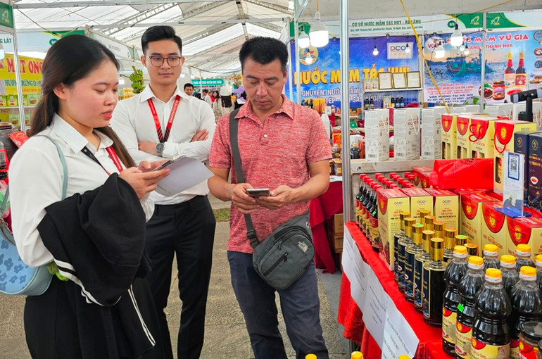 Nhân viên ngân hàng hỗ trợ người mua, bán hàng ứng dụng công nghệ thanh toán không dùng tiền mặt.