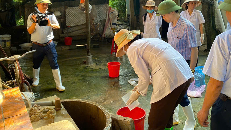 Nhân viên y tế xử lý nước giếng khơi cho hộ gia đình sau ngập lũ.