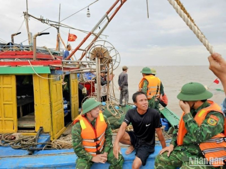 Ngư dân Tô Bá Chiến, người điều khiển tàu cá vỏ gỗ bị chìm (ngồi giữa) đang trao đổi với lực lượng biên phòng Cảng cửa khẩu Diêm Điền.