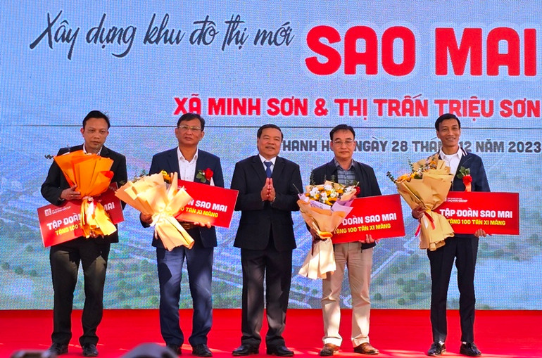 Lãnh đạo Tập đoàn Sao Mai hỗ trợ xi-măng cho các xã xây dựng công trình nông thôn mới.