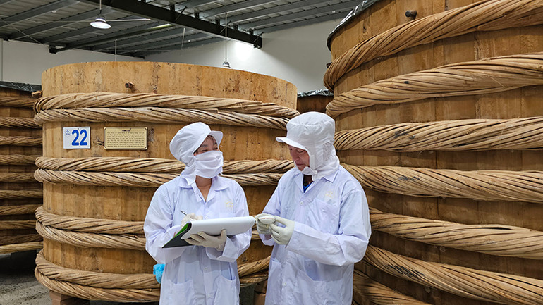 Chủ thể cùng nhân viên kiểm tra hàm lượng sản phẩm nước mắm Lê Gia.