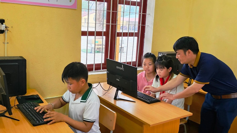 Thầy giáo hướng dẫn học sinh học tin học.