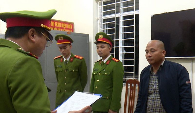 Nguyễn Văn Đoàn (bên phải) nghe Cơ quan Cảnh sát điều tra đọc các Quyết định khởi tố vụ án, khởi tố bị can và Lệnh bắt bị can để tạm giam. (Ảnh: Công an cung cấp)