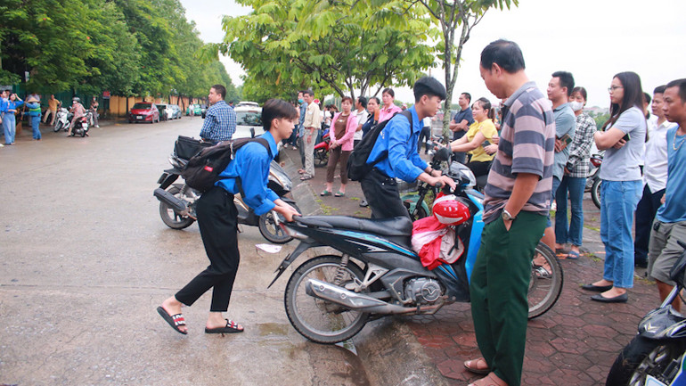 Thanh niên tình nguyện hỗ trợ phụ huynh để xe đúng vị trí. (Ảnh: QUANG HUY)