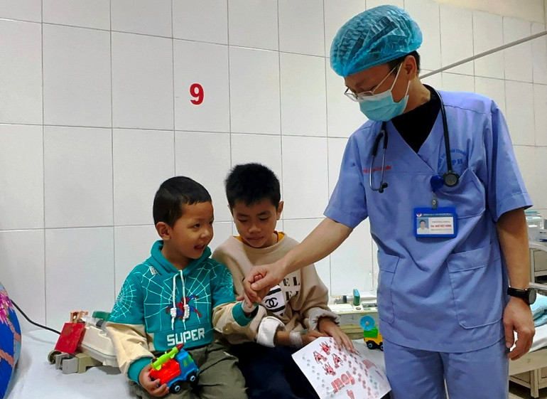 Bác sĩ thăm, kiểm tra sức khỏe 2 trẻ em trước khi xuất viện.