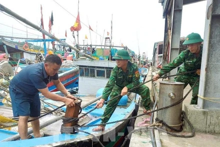 Bộ đội biên phòng tỉnh Nghệ An giúp ngư dân gia cố tàu ứng phó bão số 3. Ảnh: TTXVN