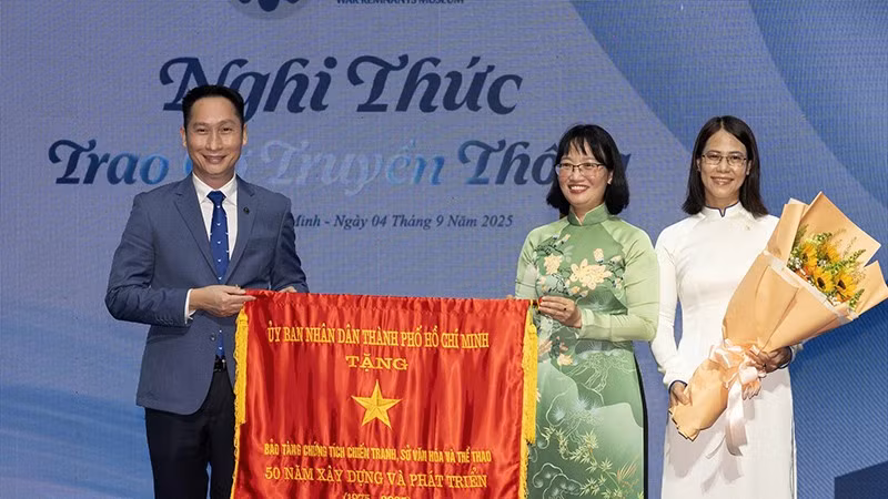 Phó Chủ tịch Ủy ban nhân dân Thành phố Hồ Chí Minh Trần Thị Diệu Thúy trao Cờ Truyền thống của Ủy ban nhân dân Thành phố cho đại diện Bảo tàng Chứng tích Chiến tranh. (Ảnh: Quốc Thanh)