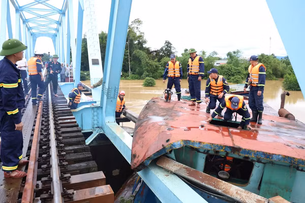 Lực lượng chức năng tiến hành cắt phần mái sà lan bị mắc kẹt với cầu đường sắt. (Ảnh: Công an tỉnh Quảng Trị)