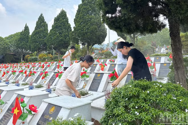 Các em học sinh dọn vệ sinh tại Nghĩa trang Liệt sĩ Vị Xuyên.